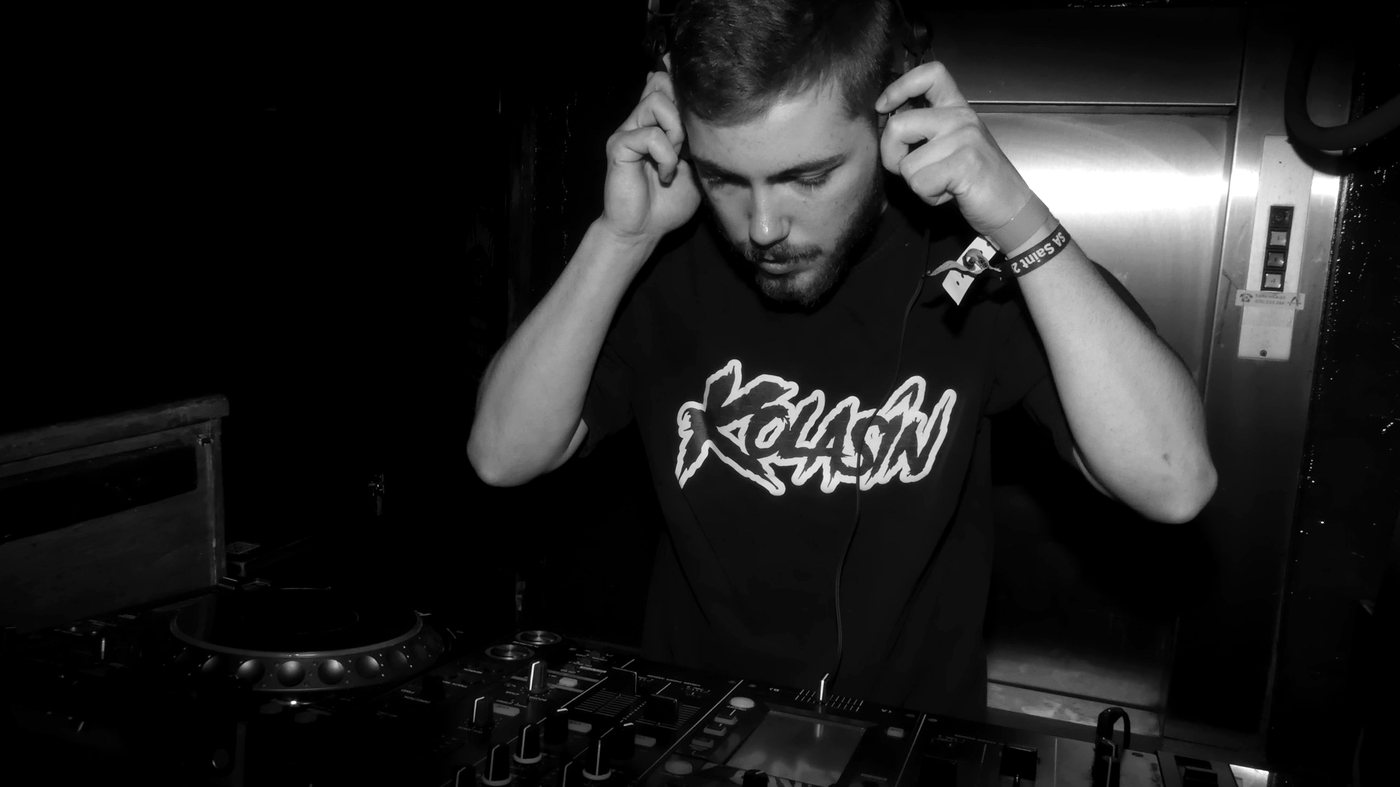 KOLASIN aux platines, casque sur les oreilles, t-shirt à son logo